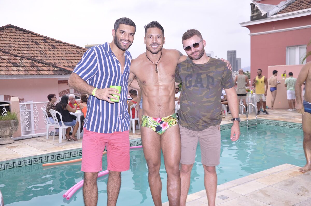 Três convidados sorridentes à beira da piscina durante pool party
