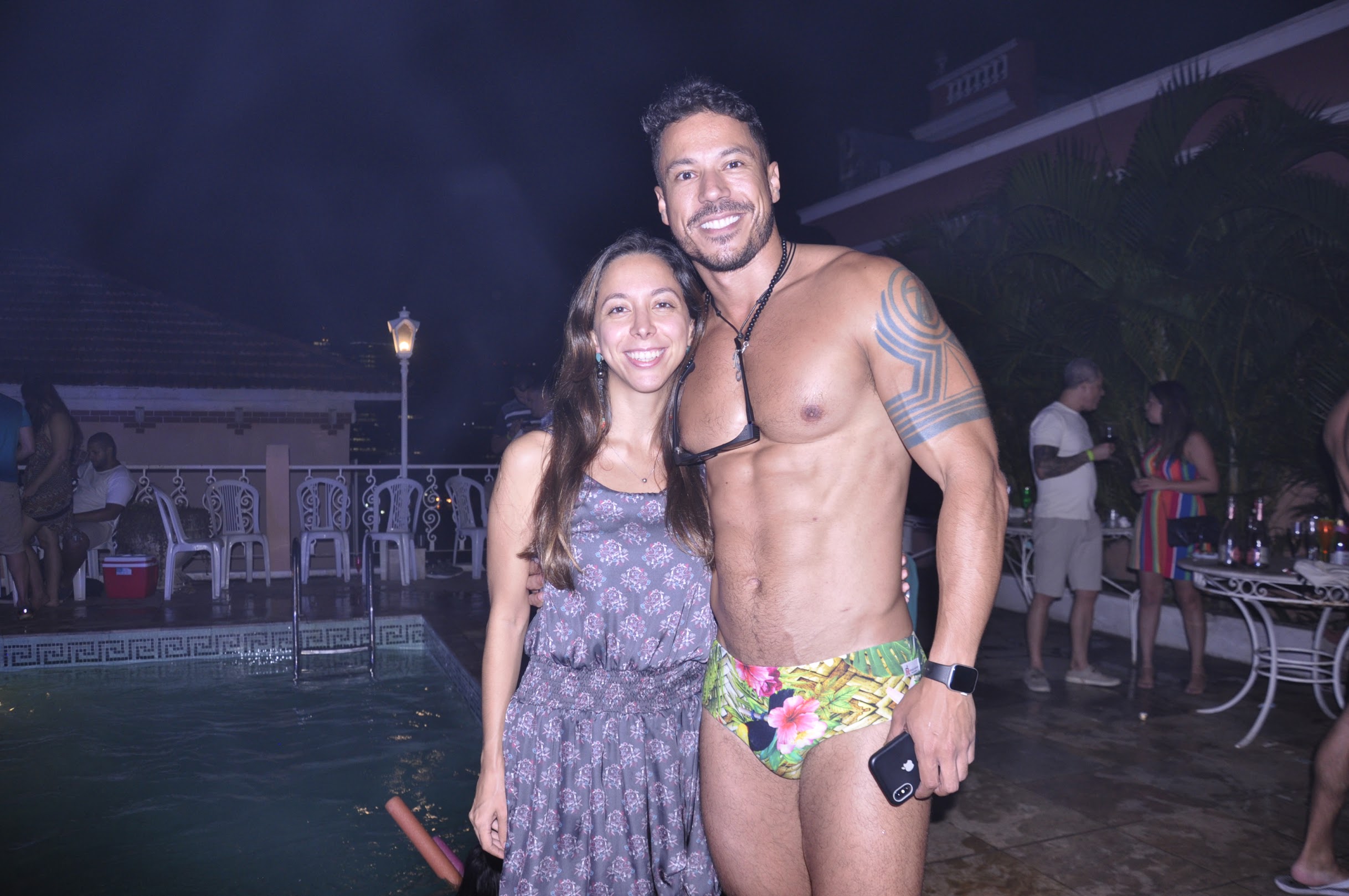 Convidados posando à beira da piscina à noite no Estica do Ulisses